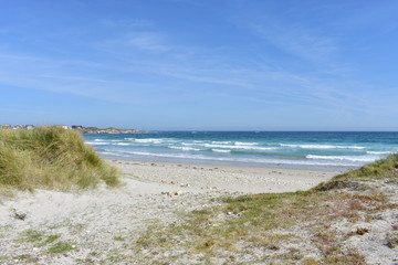 Beach with waves breaking, rocks and grass on sand dunes. Viveiro, Lugo, Galicia, Spain.