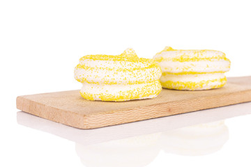 Group of two whole yellow sweet meringue on small wooden cutting board isolated on white background