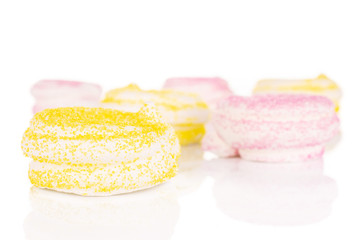 Lot of whole pink and yellow sweet meringue isolated on white background