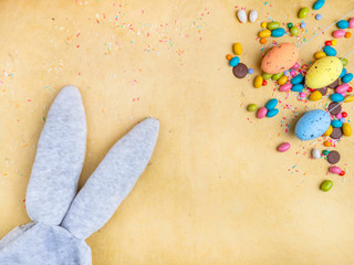 Cute creative composition with multi colored easter eggs, colorful sweets, and bunny ears. Easter and Springtime concept