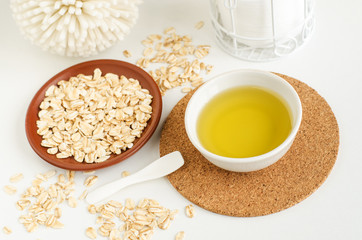 Small white bowl with olive oil and oatmeal. Homemade skin and hair treatment and zero waste concept. Copy space