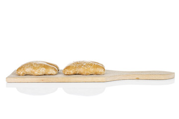 Group of two whole sweet brown gingerbread on small wooden cutting board isolated on white background
