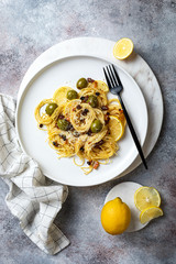 Italian pasta cacio e pepe, spaghetti mixed with grated cheese, green olives, lemon and raisins