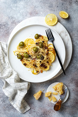 Italian pasta cacio e pepe, spaghetti mixed with grated cheese, green olives, lemon and raisins