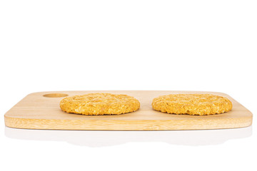 Group of two whole sweet golden oat cookie on bamboo cutting board isolated on white background