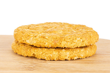 Group of two whole sweet golden oat cookie on bamboo cutting board isolated on white background