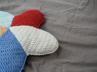 Closeup hand made multicolored yarn knitted pillow in the shape of a starfish on a gray background. Natural materials for the interior. Chemical free textile