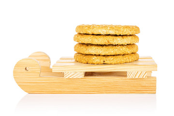 Group of four whole sweet golden oat cookie with wooden sledge isolated on white background