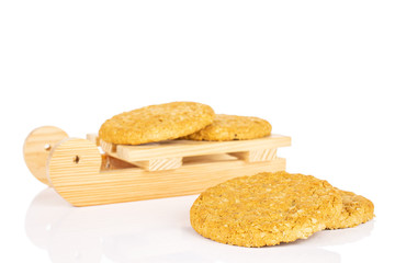 Group of four whole sweet golden oat cookie with wooden sledge isolated on white background