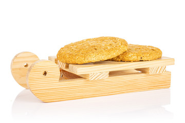 Group of two whole sweet golden oat cookie with wooden sledge isolated on white background