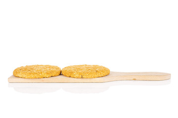 Group of two whole sweet golden oat cookie on small wooden cutting board isolated on white background