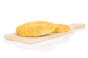 Group of two whole sweet golden oat cookie on small wooden cutting board isolated on white background