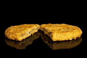 Group of two halves of sweet golden oat cookie isolated on black glass