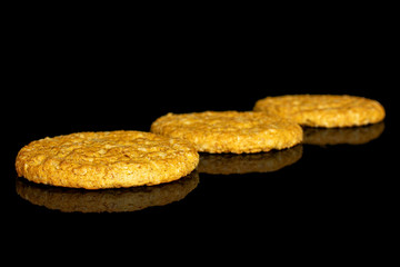 Group of three whole sweet golden oat cookie placed diagonally isolated on black glass