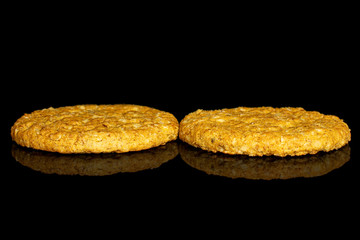 Group of two whole sweet golden oat cookie isolated on black glass