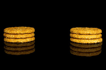 Group of six whole sweet golden oat cookie in two columns isolated on black glass