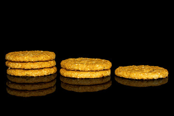 Group of six whole sweet golden oat cookie isolated on black glass
