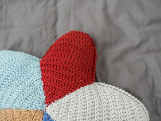 Closeup hand made multicolored yarn knitted pillow in the shape of a starfish on a gray background. Natural materials for the interior. Chemical free textile