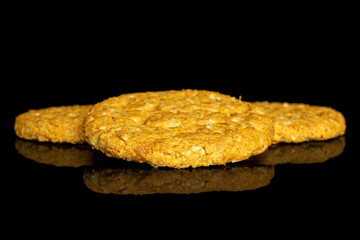 Group of three whole sweet golden oat cookie isolated on black glass