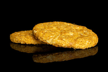 Group of two whole sweet golden oat cookie isolated on black glass