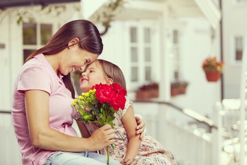 Happy beautiful mother and daughter hugging with a bouquet