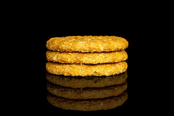 Group of three whole sweet golden oat cookie in column isolated on black glass