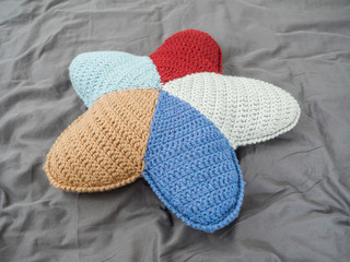Closeup hand made multicolored yarn knitted pillow in the shape of a starfish on a gray background. Natural materials for the interior. Chemical free textile