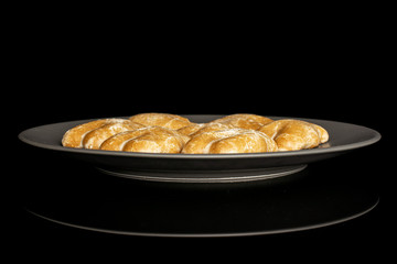 Group of seven whole sweet brown gingerbread on gray ceramic plate isolated on black glass