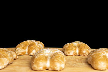 Group of five whole sweet brown gingerbread on bamboo cutting board isolated on black glass