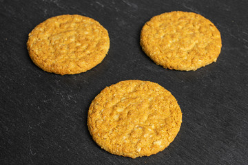 Group of three whole sweet golden oat cookie on grey stone