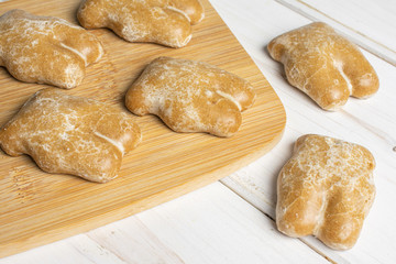 Group of six whole sweet brown gingerbread on bamboo cutting board on white wood