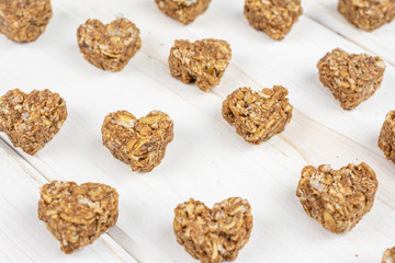 Lot of whole healthy brown cereal heart with cocoa on white wood