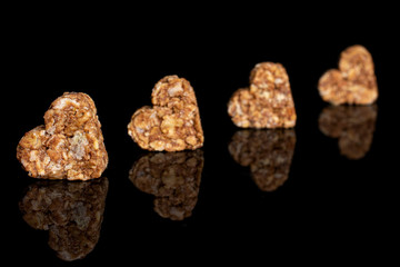 Group of four whole healthy brown cereal heart with cocoa isolated on black glass