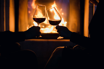 Young couple have romantic dinner with wine over fireplace background