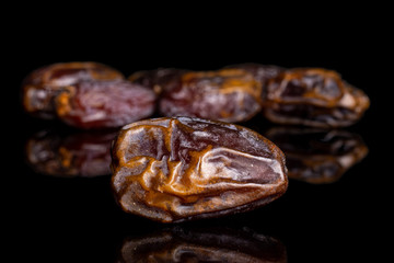Lot of whole dry brown date fruit isolated on black glass