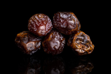 Group of five whole dry brown date fruit isolated on black glass