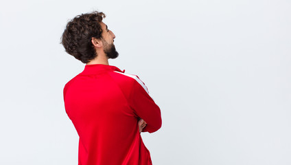 young bearded man back view feeling happy, proud and hopeful, wondering or thinking, looking up to...