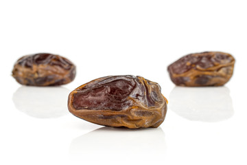 Group of three whole dry brown date fruit one is in the front isolated on white background
