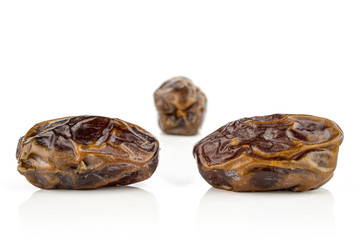 Group of three whole dry brown date fruit isolated on white background