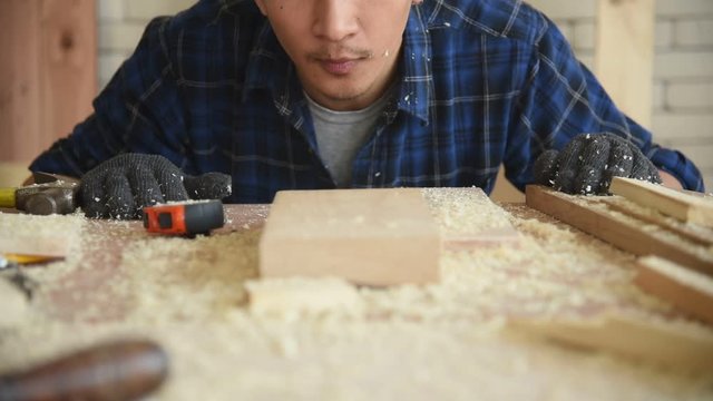 Young Asian group man worker blow sawdust in workshop for build diy wood furniture