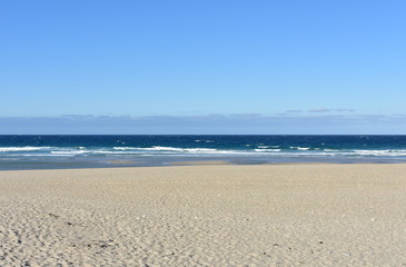 Fototapeta na wymiar Summer landscape with wild beach with waves breaking and blue sky. Arteixo, Coruña, Galicia, Spain.
