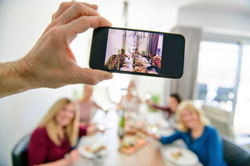 Cellphone view of Group of attractive mature people eating sushi at home