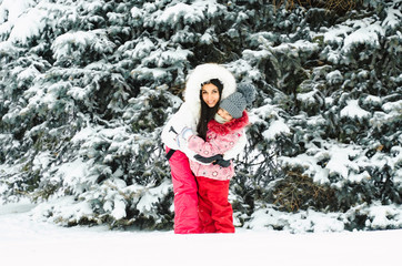 Young woman and her baby throwing snow, happy and fun