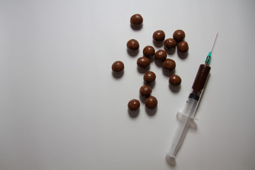 Chocolate candies, a syringe containing chocolate on a white background
