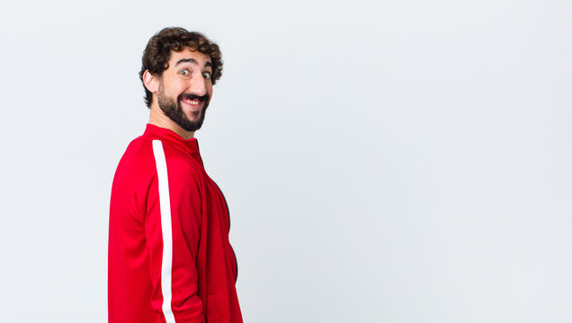 young bearded man back view looking happy and goofy with a broad, fun, loony smile and eyes wide open against copy space wall