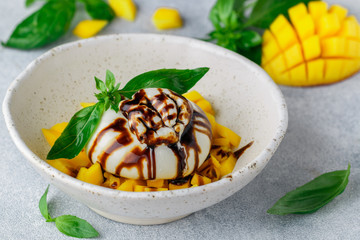 Delicatessen  burrata cheese with mango tartare with green Basil and balsamic in a white plate on a...