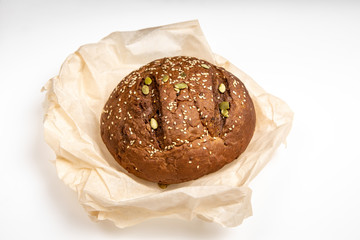 Tasty fresh baked loaf of dark bread with sesame seeds on white background