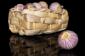 Lot of whole fresh purple single clove garlic in bast basket isolated on black glass