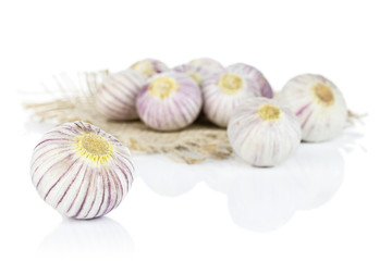 Obraz na płótnie Canvas Lot of whole fresh purple single clove garlic on natural sackcloth isolated on white background