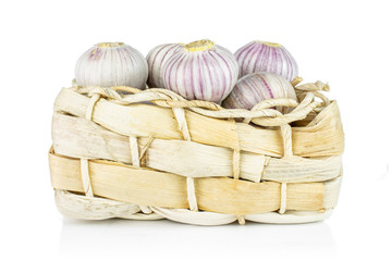 Lot of whole fresh purple single clove garlic in bast basket isolated on white background